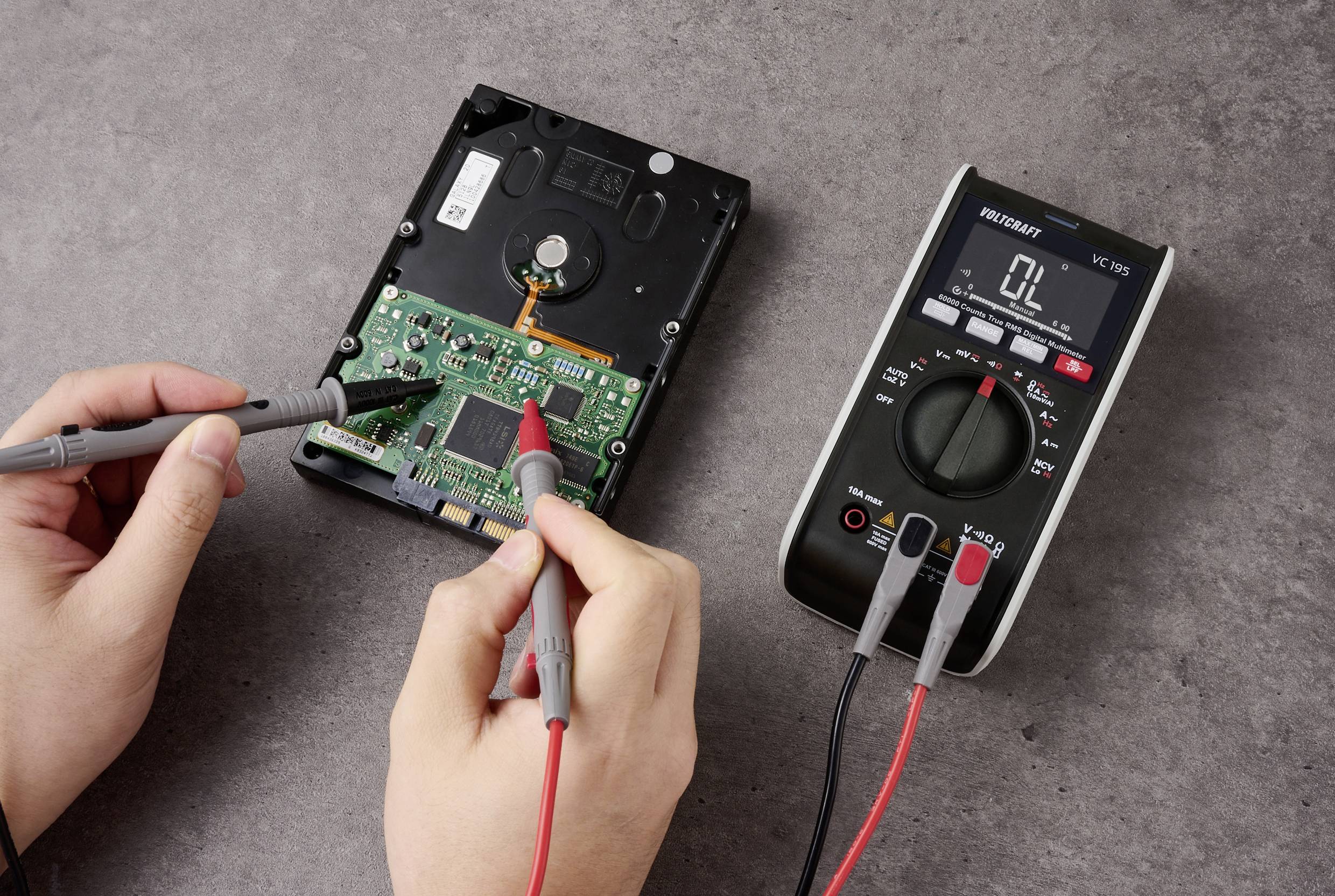 Eine Person verwendet ein Multimeter, um eine geöffnete Festplatte zu testen und elektrische Werte auf der Leiterplatte zu messen.