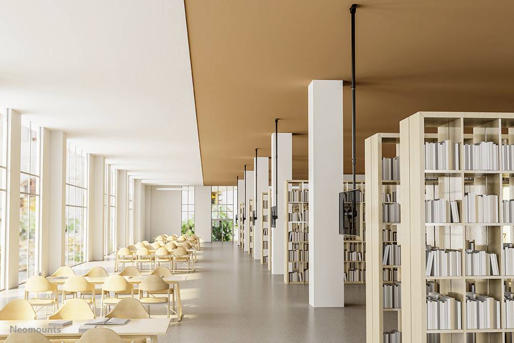 Heller, moderner Lesesaal einer Bibliothek mit langen Tischen und Bücherregalen. Fenster lassen viel Tageslicht herein.