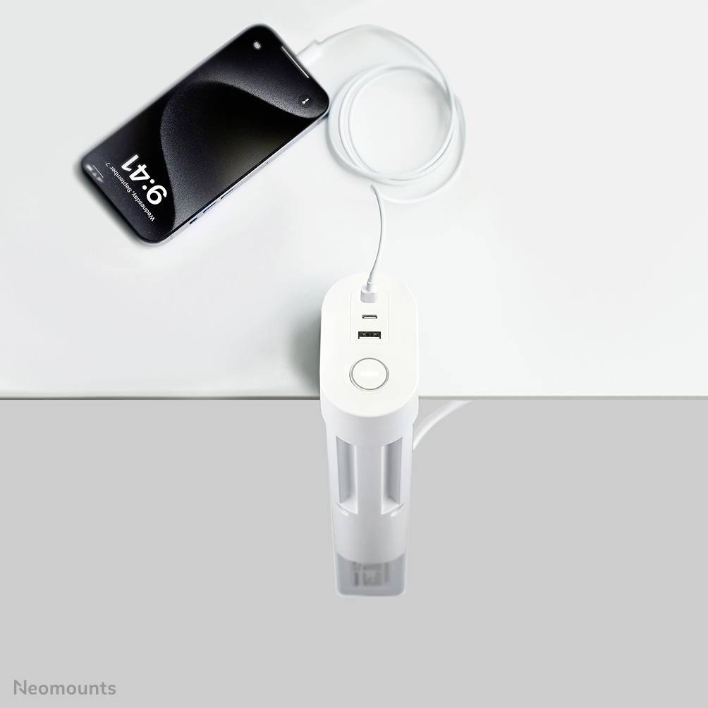 Ein Smartphone wird mit einem Tischladegerät verbunden, das an der Tischkante befestigt ist. Ladegerät hat zwei USB-Anschlüsse.