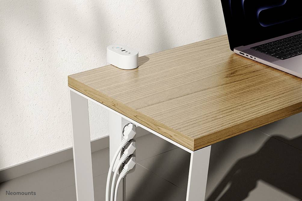 Ein weißer Schreibtisch mit Holztischplatte, auf dem Kabel ordentlich durch eine Halterung geführt sind. Ein Laptop steht am rechten Rand.