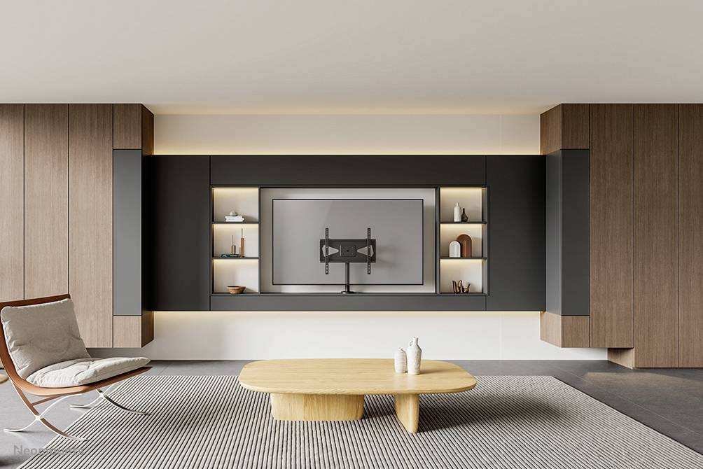 Moderner Wohnraum mit Wandregalen, einem großen Flachbildschirm an der Wand, einer Lounge-Sessel und einem Holztisch auf Teppich.