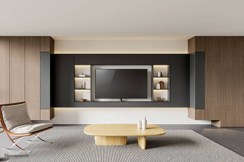Modernes Wohnzimmer mit hölzernem Akzent. Im Zentrum ein großer Flachbildfernseher, umgeben von Regalen und Deko. Minimalistisches Design.