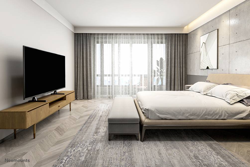 Ein modernes Schlafzimmer mit großem Bett, Wandspiegel, Fernseher auf Holzschrank und Fenster mit blickdichten Vorhängen.