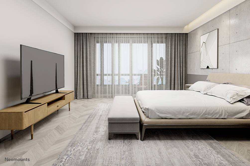 Ein modernes Schlafzimmer mit einem großen Bett, einem Holzfernsehtisch mit Flachbildfernseher und einem großen Fenster mit Vorhängen.