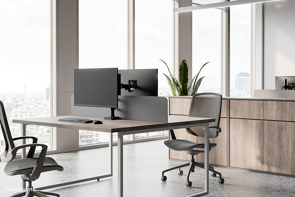 Moderne Büroumgebung mit zwei Bürostühlen und einem Schreibtisch mit Dual-Monitoraufbau. Fenster im Hintergrund mit Stadtblick.