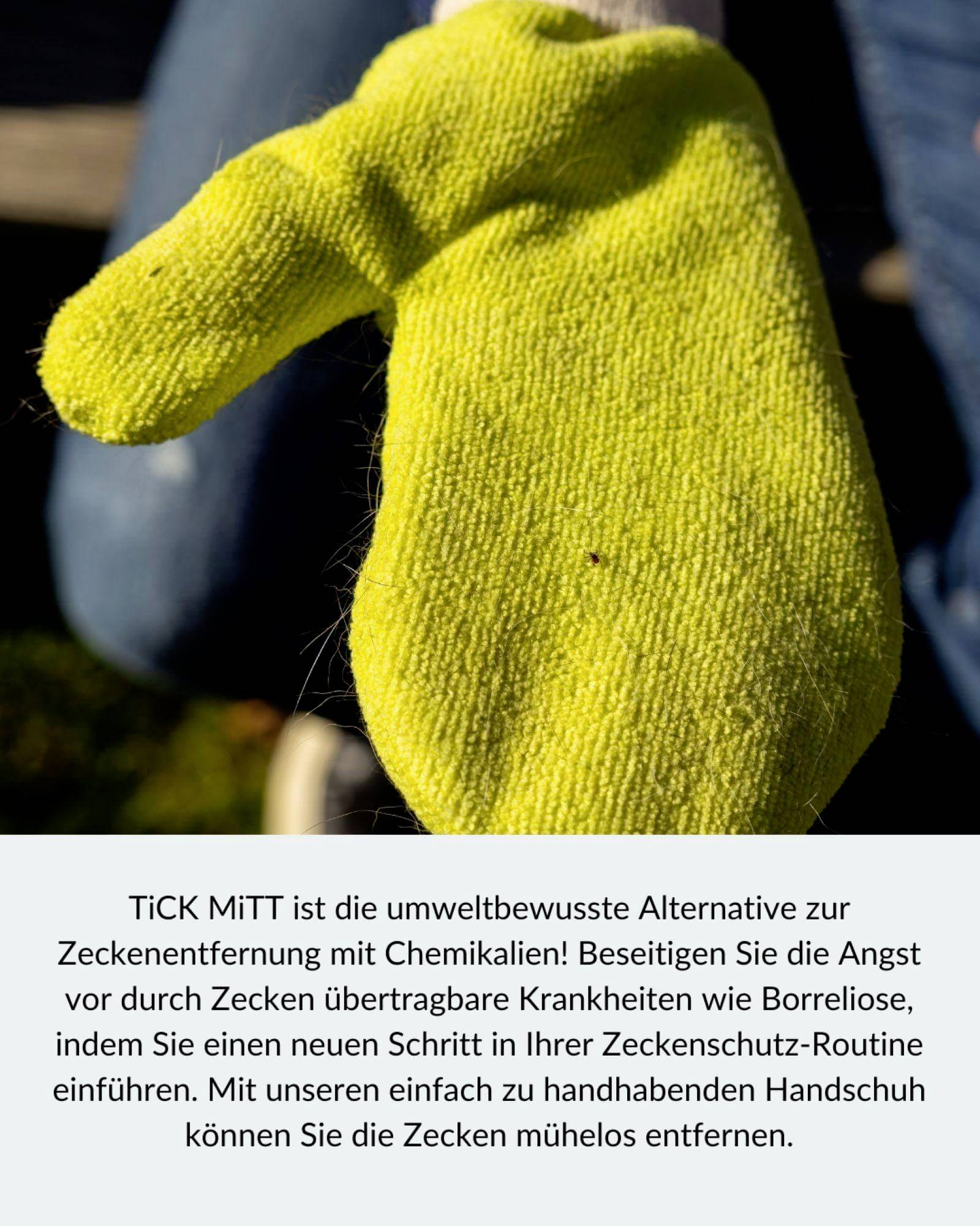 Eine neon-gelbe Hand in einem gestrickten Handschuh hält einen braunen Gegenstand, möglicherweise eine Zecke, vor unscharfem Hintergrund.