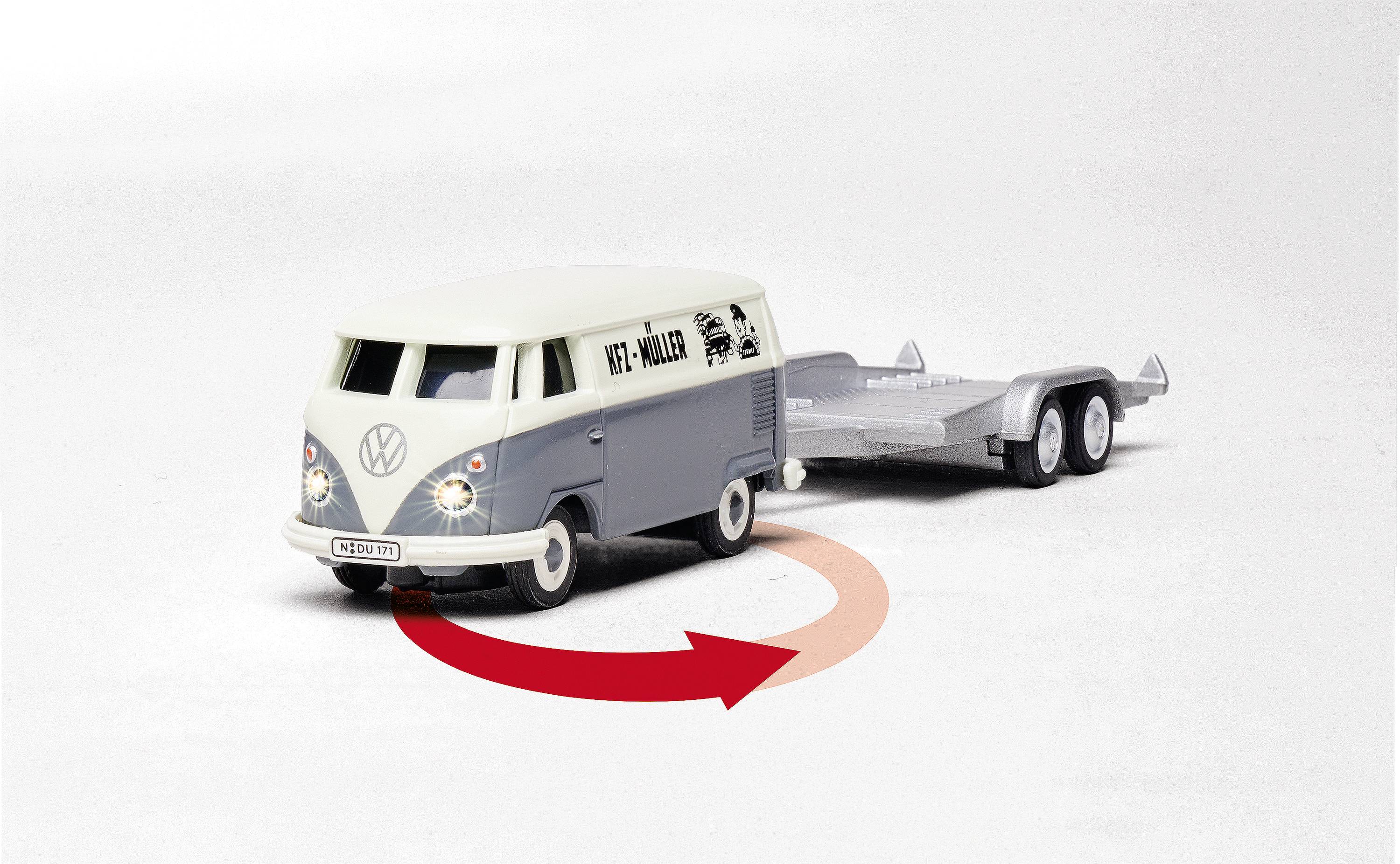 Ein Modell eines VW-Busses mit Anhänger steht schräg nach links. Eine rote Pfeildarstellung deutet eine Linkskurve an.