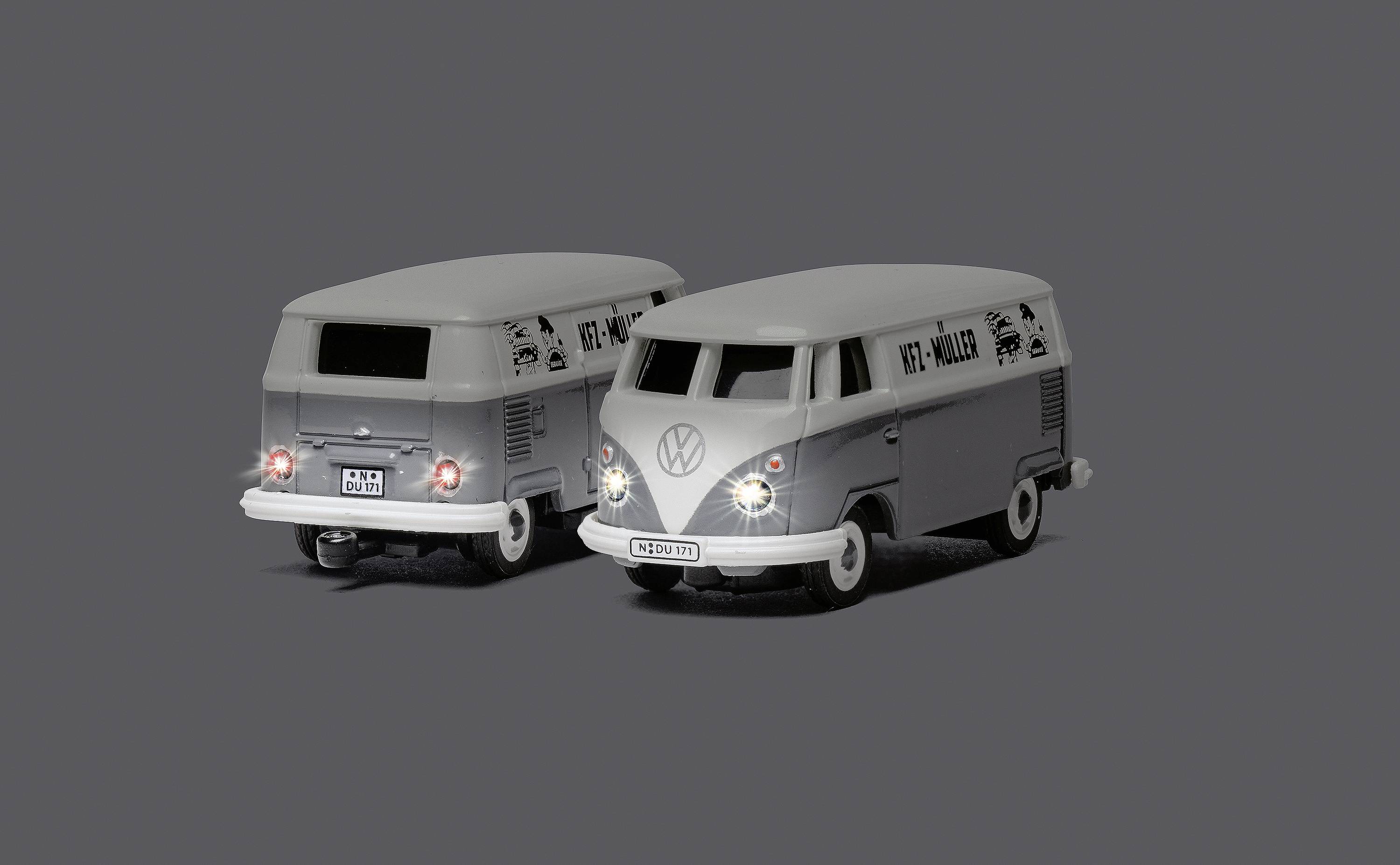 Zwei graue Spielzeugmodelle eines klassischen VW-Busses, eines von vorne und eines von hinten, auf neutralem Hintergrund.