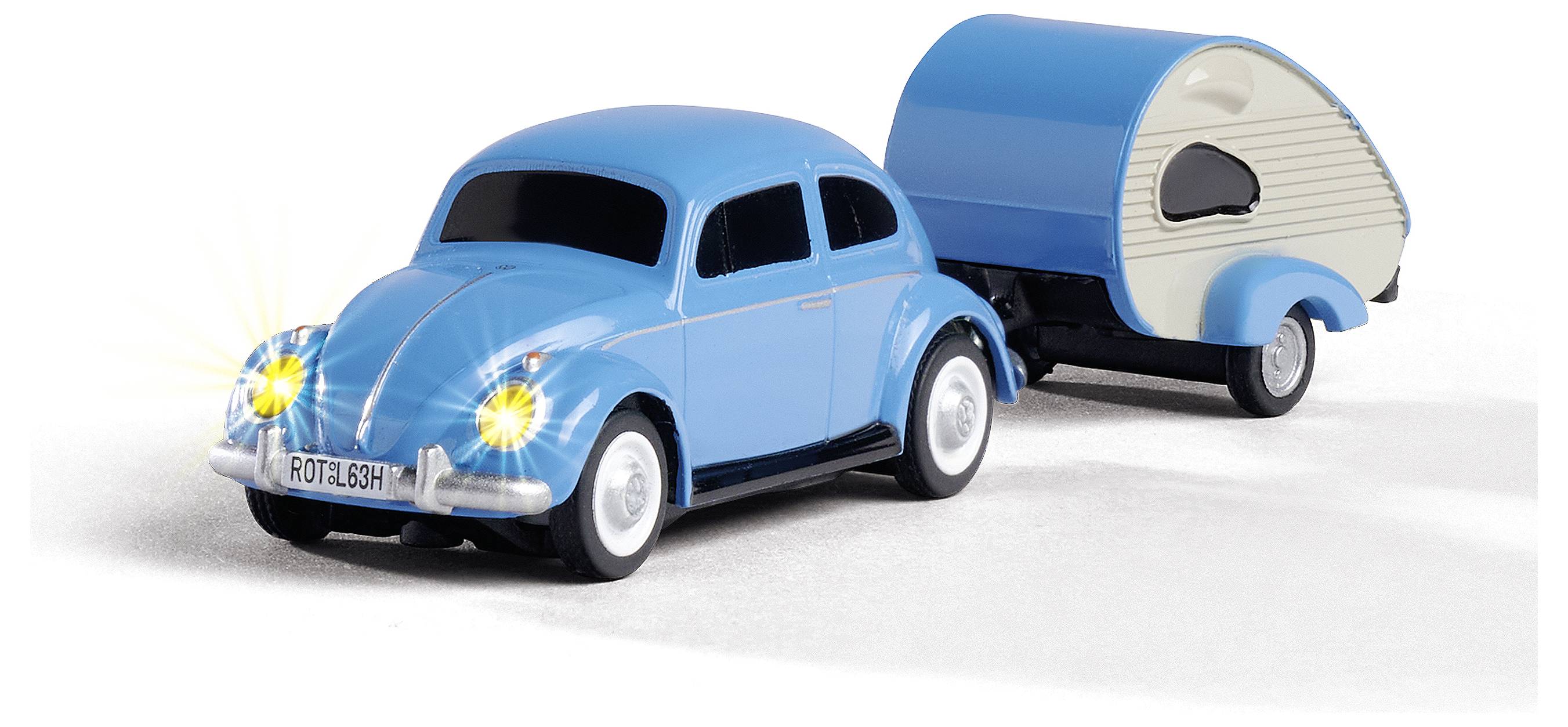 Blaues Spielzeugauto in Käferform mit leuchtenden Scheinwerfern, zieht einen blauen Mini-Wohnanhänger auf hellem Hintergrund.