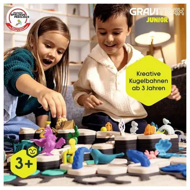 Zwei Kinder spielen mit einem GraviTrax Junior Kugelbahnsystem. Aufschrift: 'Kreative Kugelbahnen ab 3 Jahren', geeignet ab 3+.