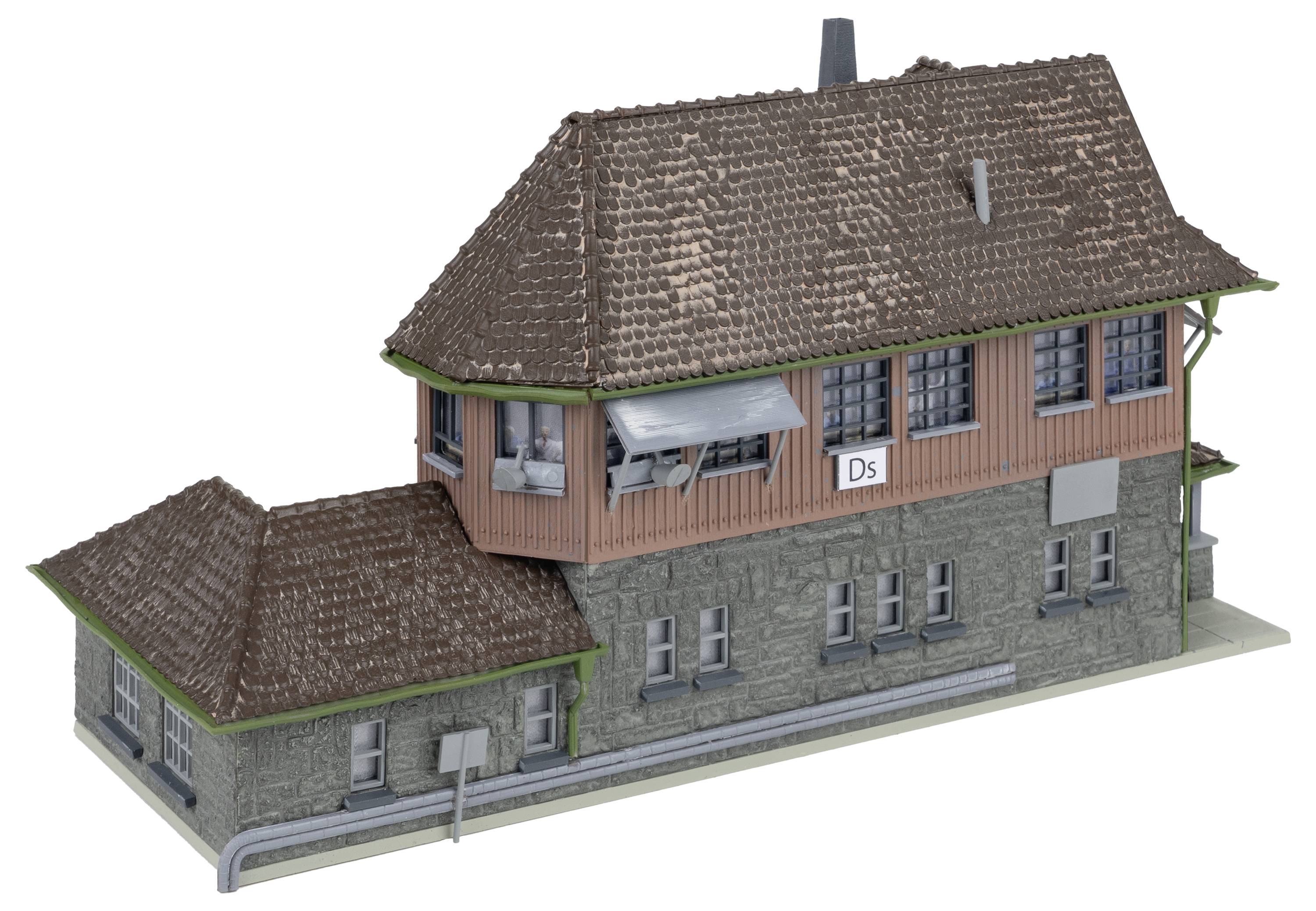 Ein Modell eines alten Bahnhofsgebäudes mit Ziegeldach und einem Schild mit der Aufschrift 'Ds'. Gebäude im Fachwerkstil.