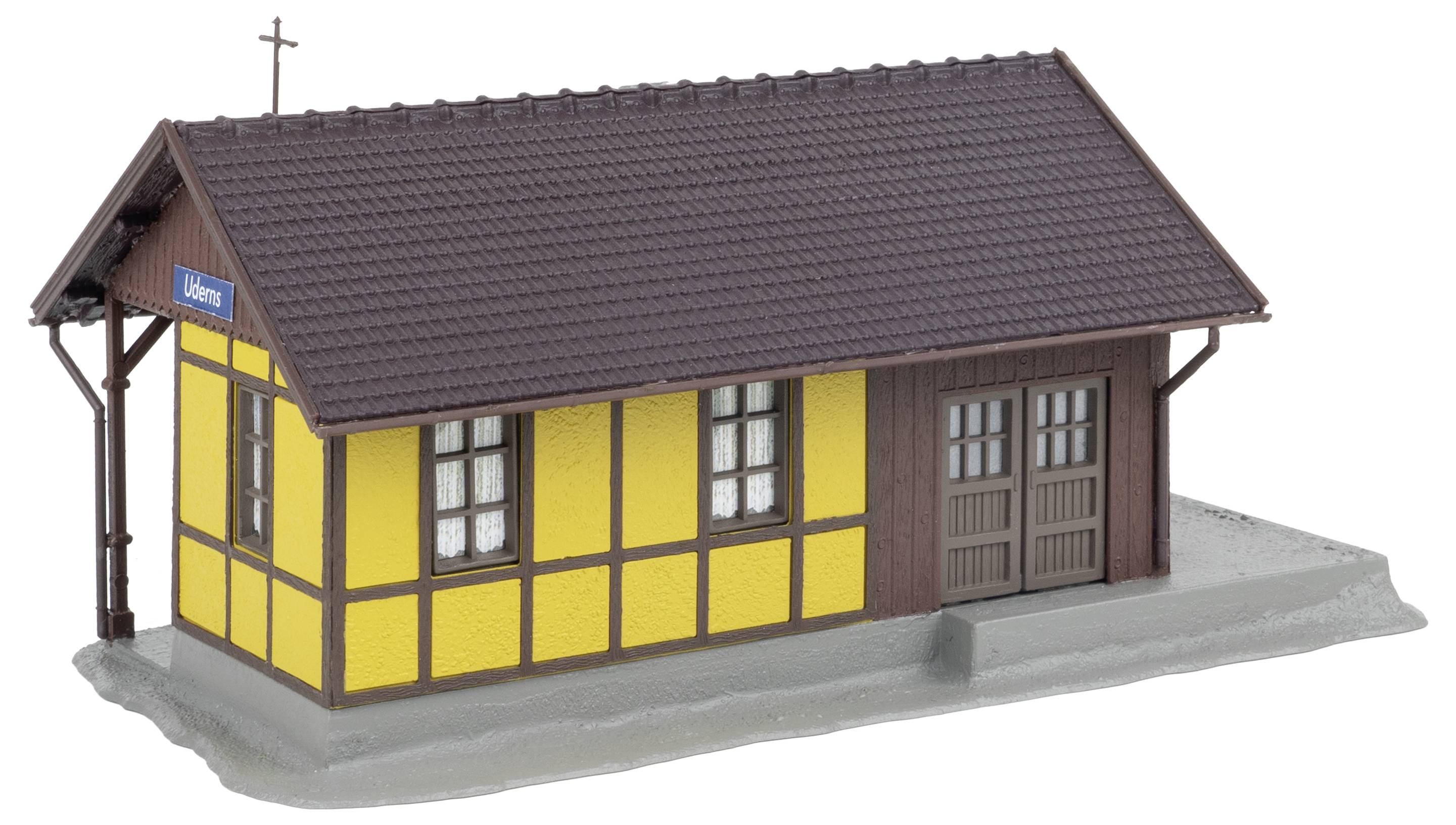 Gelbes und braunes Fachwerkgebäude mit Kreuz auf dem Dach und einem Schild 'Uhler' an der Seite.