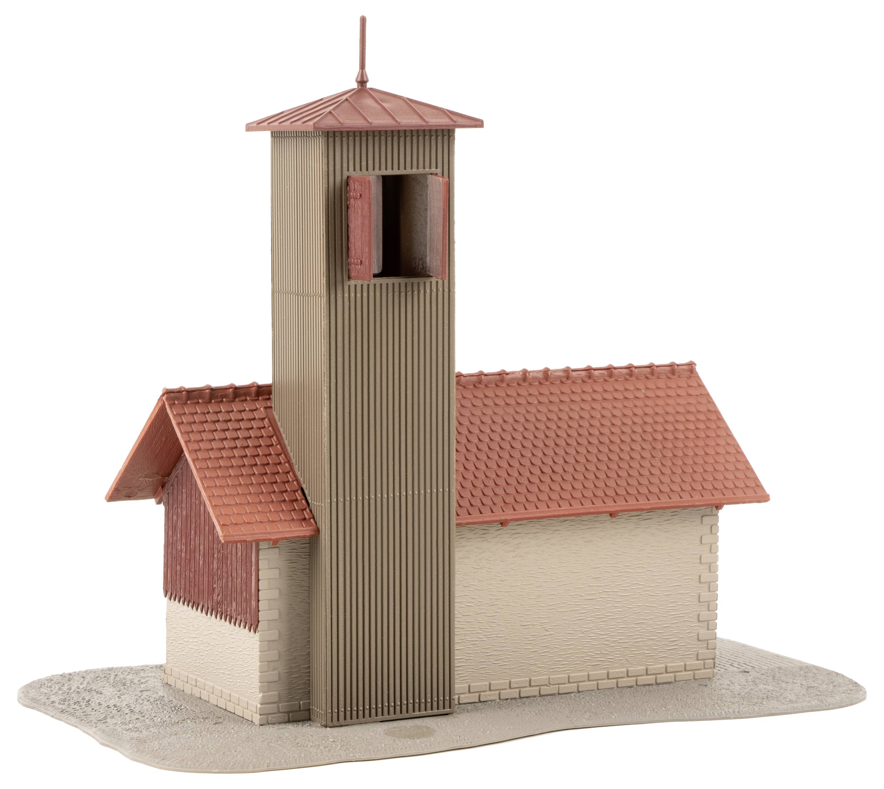 Ein Modell einer kleinen Kirche mit rotem Ziegeldach und hohem Glockenturm. Das Gebäude ist auf einer sandfarbenen Basis platziert.