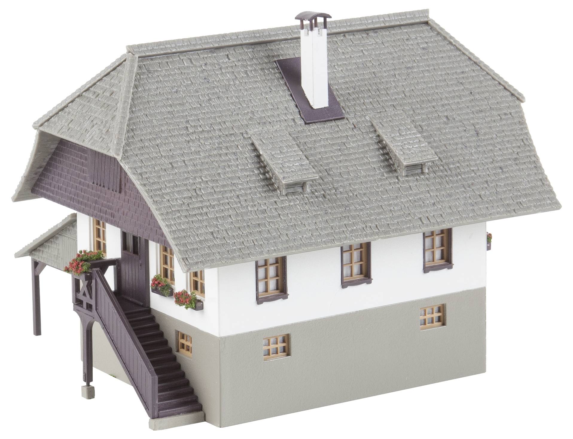 Ein Modell eines traditionellen Hauses mit grauem Schindeldach, weißen Wänden und Holzverzierungen. Treppe führt zum Eingang.