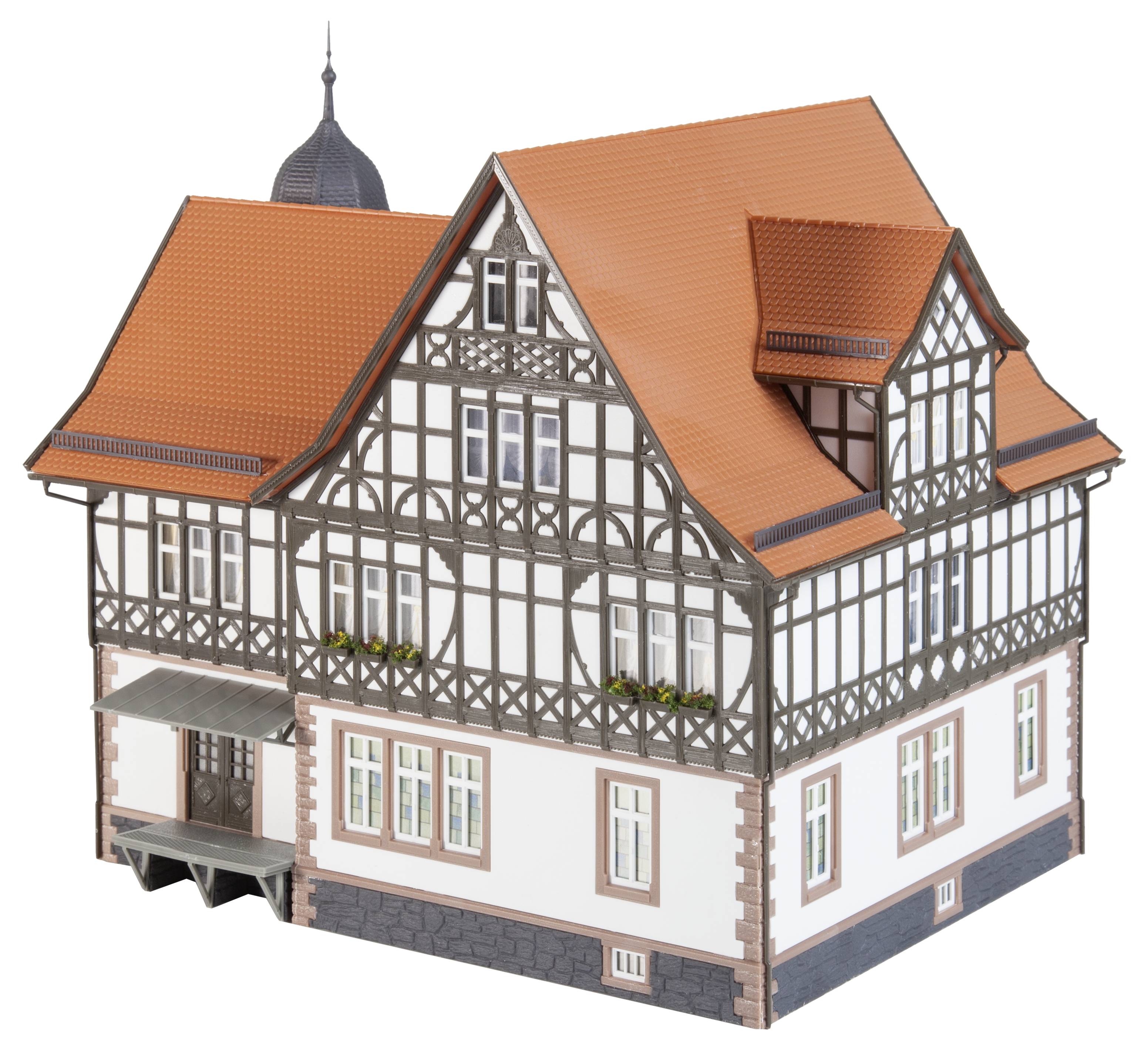 Ein Fachwerkhaus-Modell mit rotem Ziegeldach und dunkelbraunen Holzverzierungen, zeigt detaillierte Architektur und Fensterblumen.