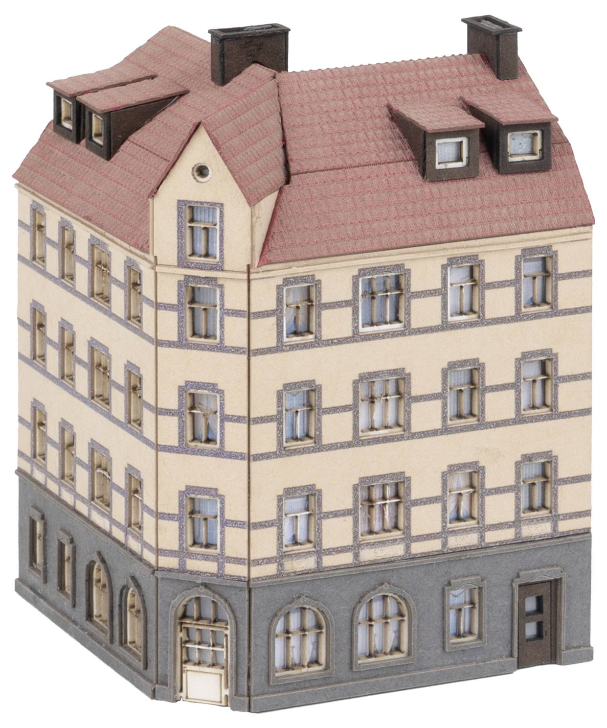 Ein kleines Modellgebäude mit vier Stockwerken, rotem Spitzdach und mehreren Fenstern. Das Erdgeschoss hat ein Geschäft mit großen Fenstern.