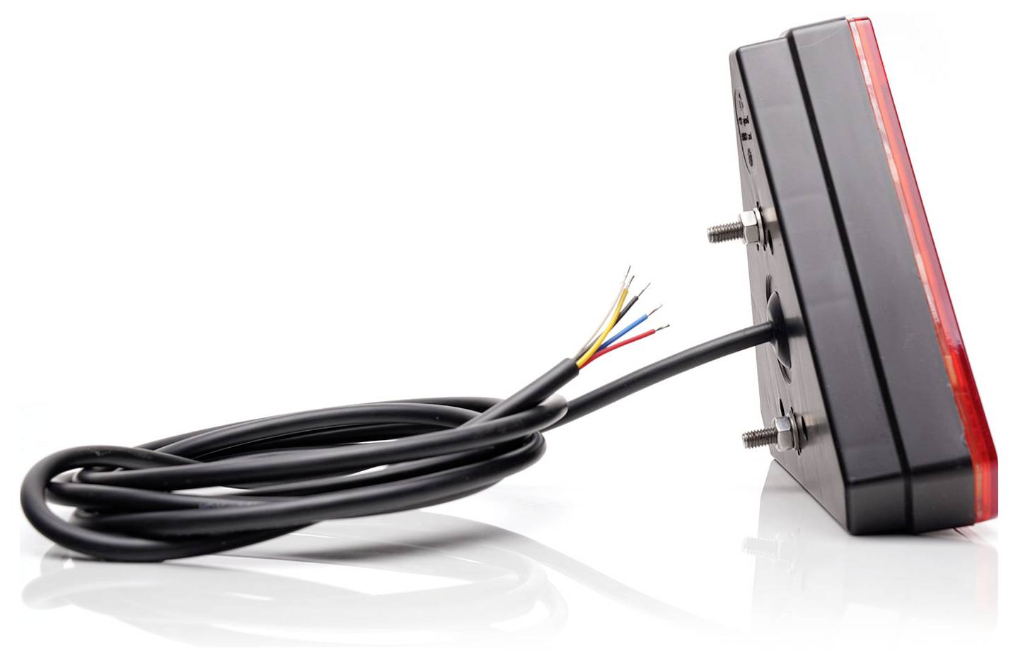 Ein rechteckiges Rücklicht mit roter Linsenkappe und freiliegenden Kabeln. Es hat zwei Befestigungsschrauben und ist auf einer reflektierenden Oberfläche platziert.