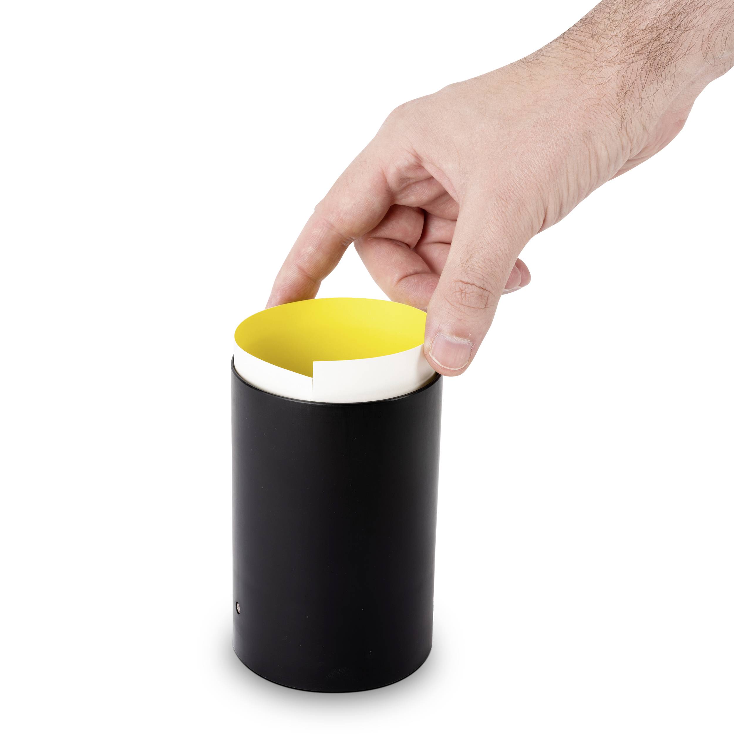 Hand legt gelben Einsatz in schwarzen Behälter.