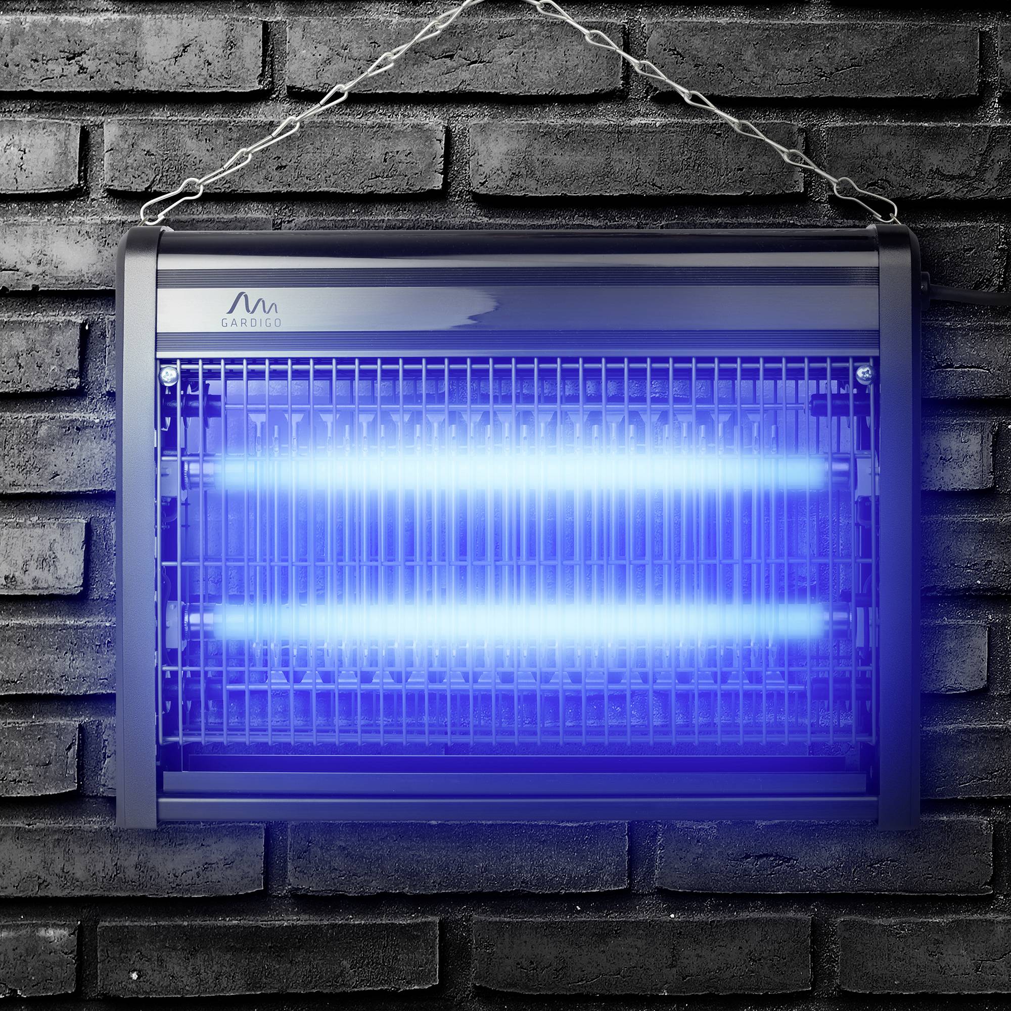 Elektrischer Insektenvernichter mit blauem UV-Licht, an einer Ziegelwand hängend, zur Abwehr von fliegenden Insekten.