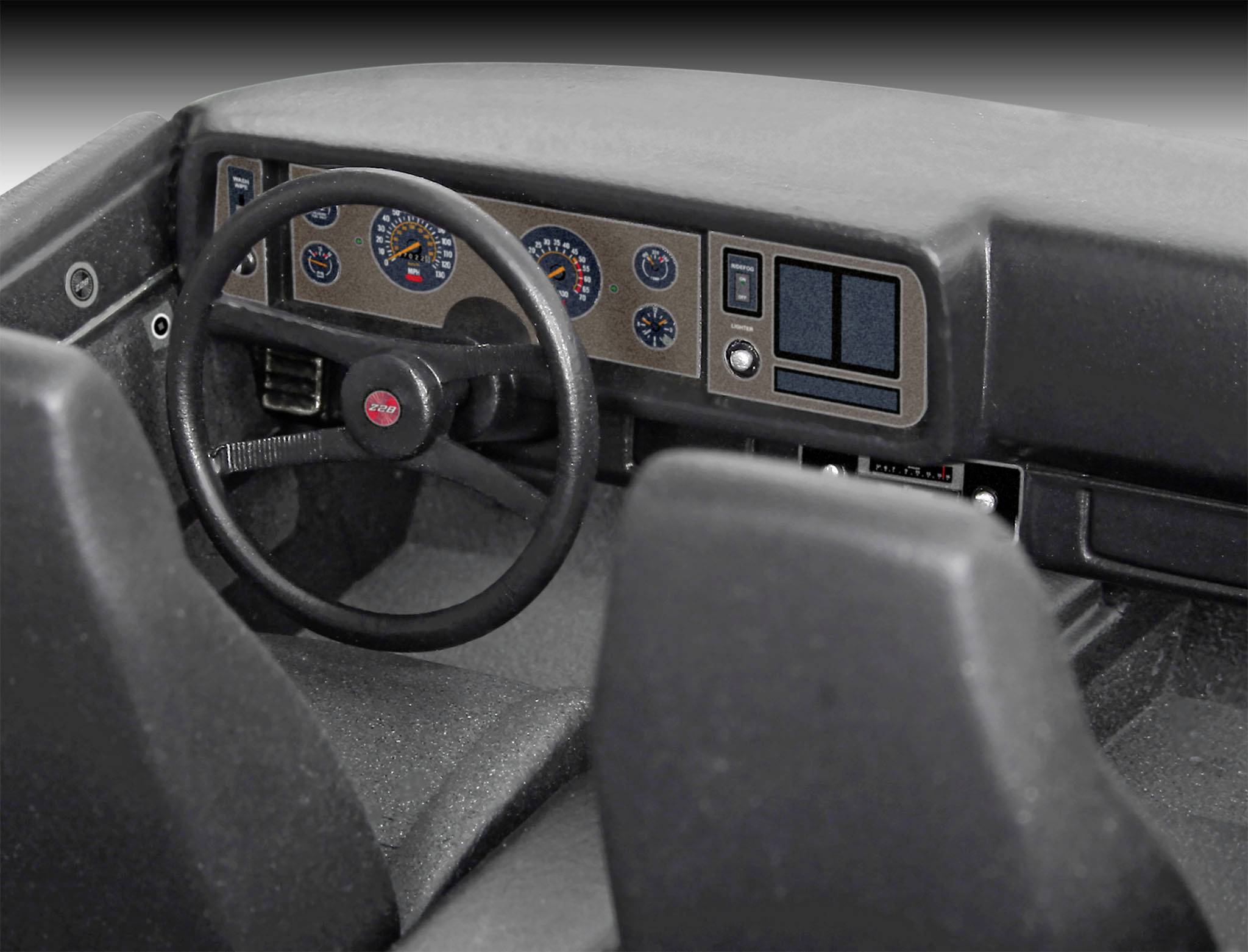 Innenraum eines Autos mit Lenkrad, Armaturenbrett und zwei Sitzen. Instrumententafel mit Tacho, Drehzahlmesser und weiteren Anzeigen.