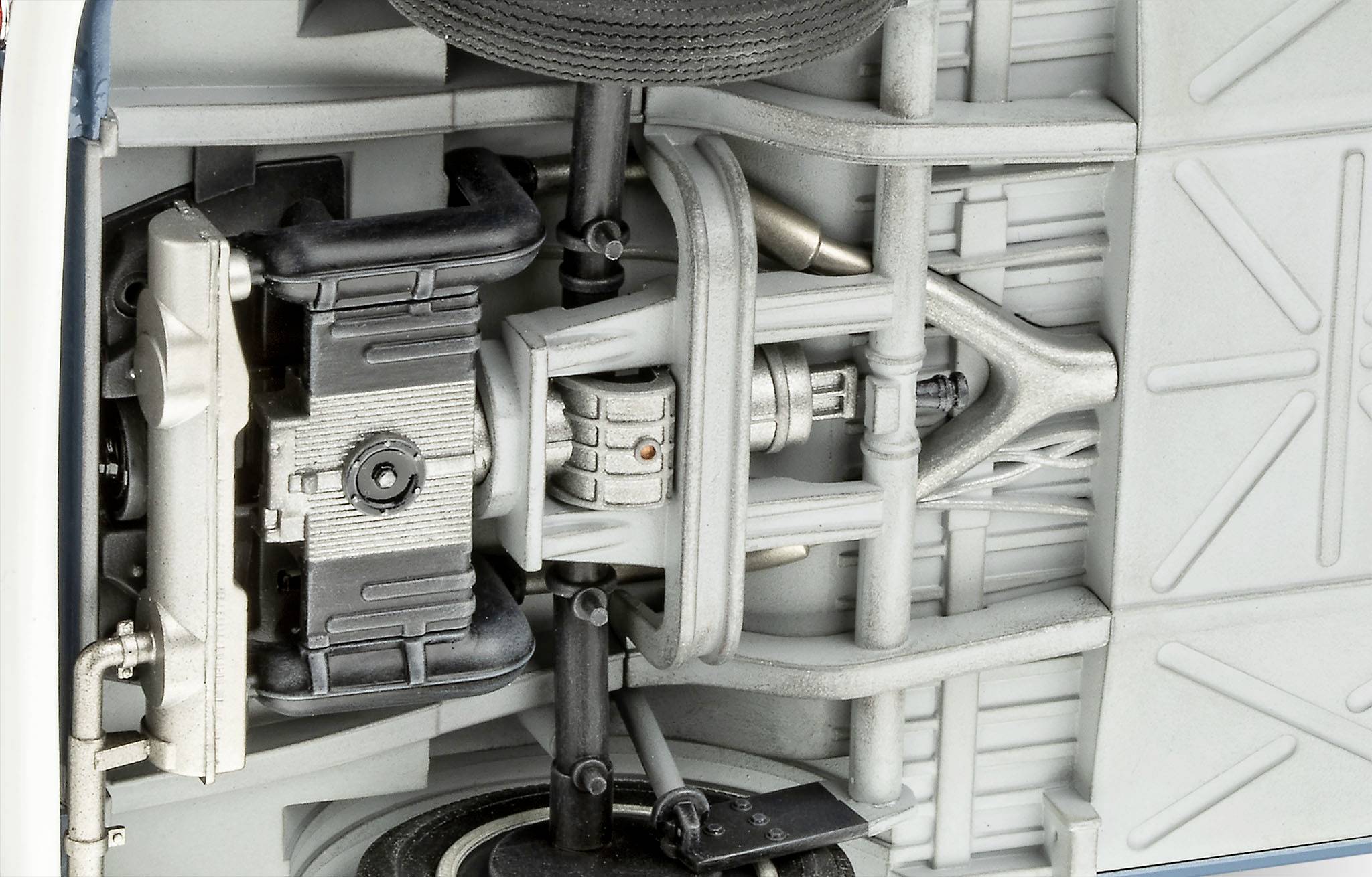 Untere Ansicht einer detaillierten Fahrzeugachse und Federung mit Stoßdämpfer, Antriebsstrang und verschiedenen mechanischen Komponenten.