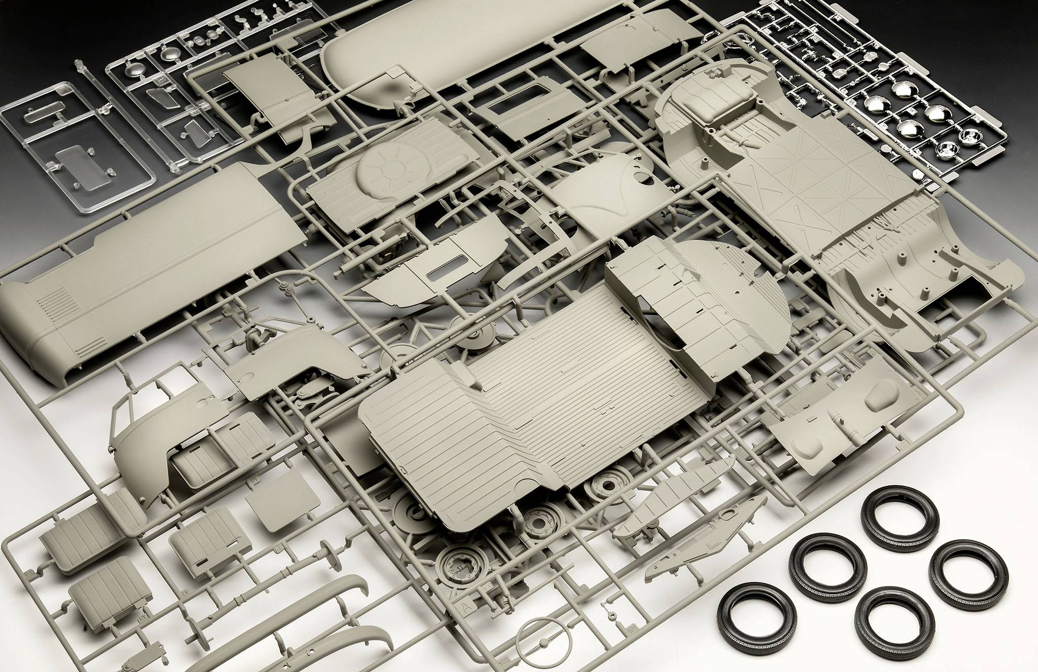 Bauteile eines Modellbausatzes für einen LKW, einschließlich Räder und Karosserieteile, in einem Plastikrahmen angeordnet.