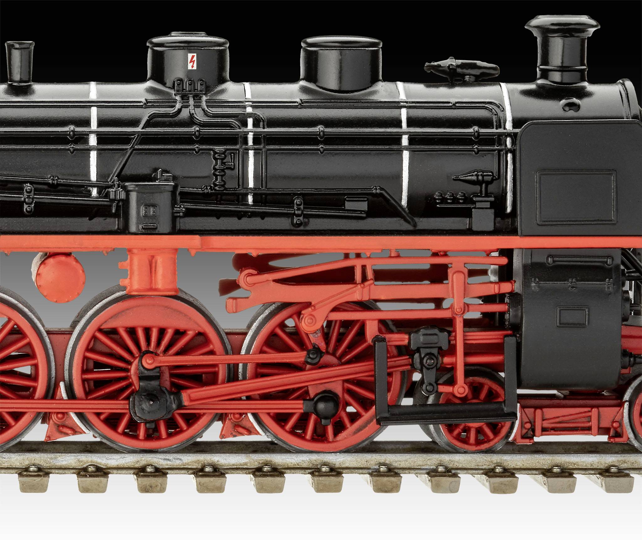 Schwarze Dampflokomotive mit roten Rädern und Details, auf Schienen stehend. Detaillierte Anordnung von Rohren und Mechanik sichtbar.