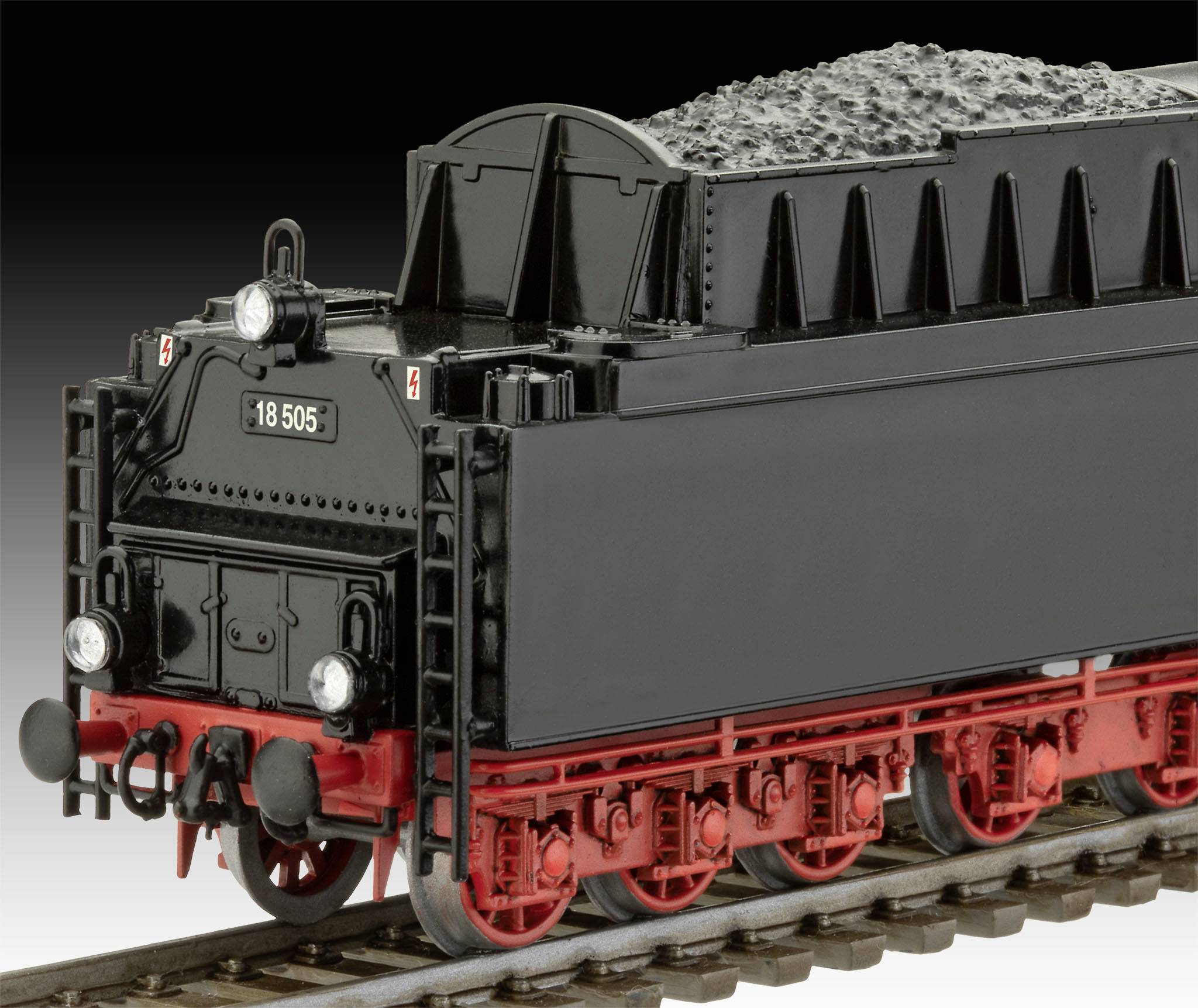 Schwarzes Modell eines historischen Tender-Anhängers einer Dampflokomotive mit roten Details auf einem Gleis, mit Kohle beladen.