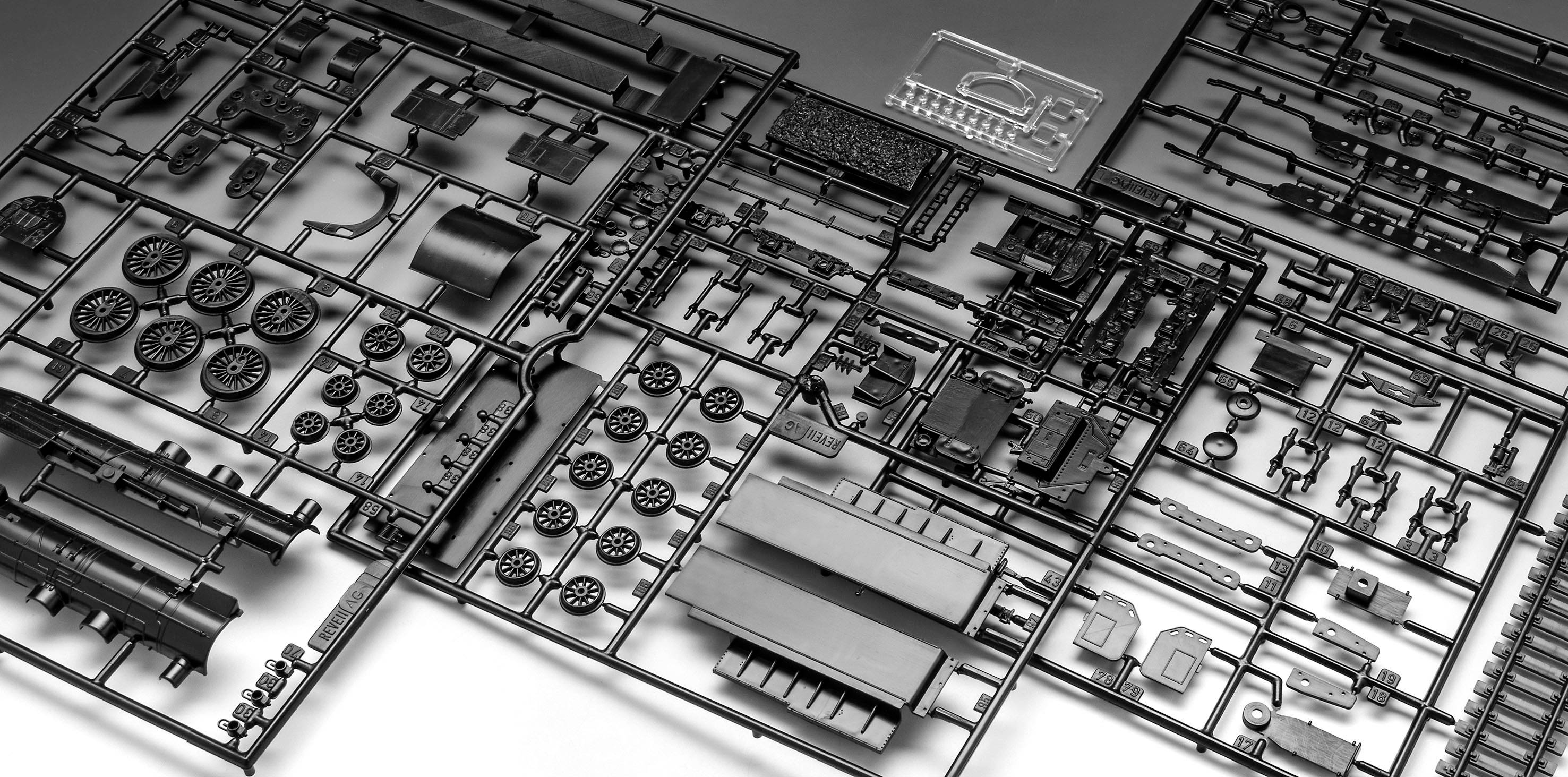 Schwarzer Kunststoffmodellbausatz mit verschiedenen Teilen und Details, bereit zum Zusammenbau eines Fahrzeugs.