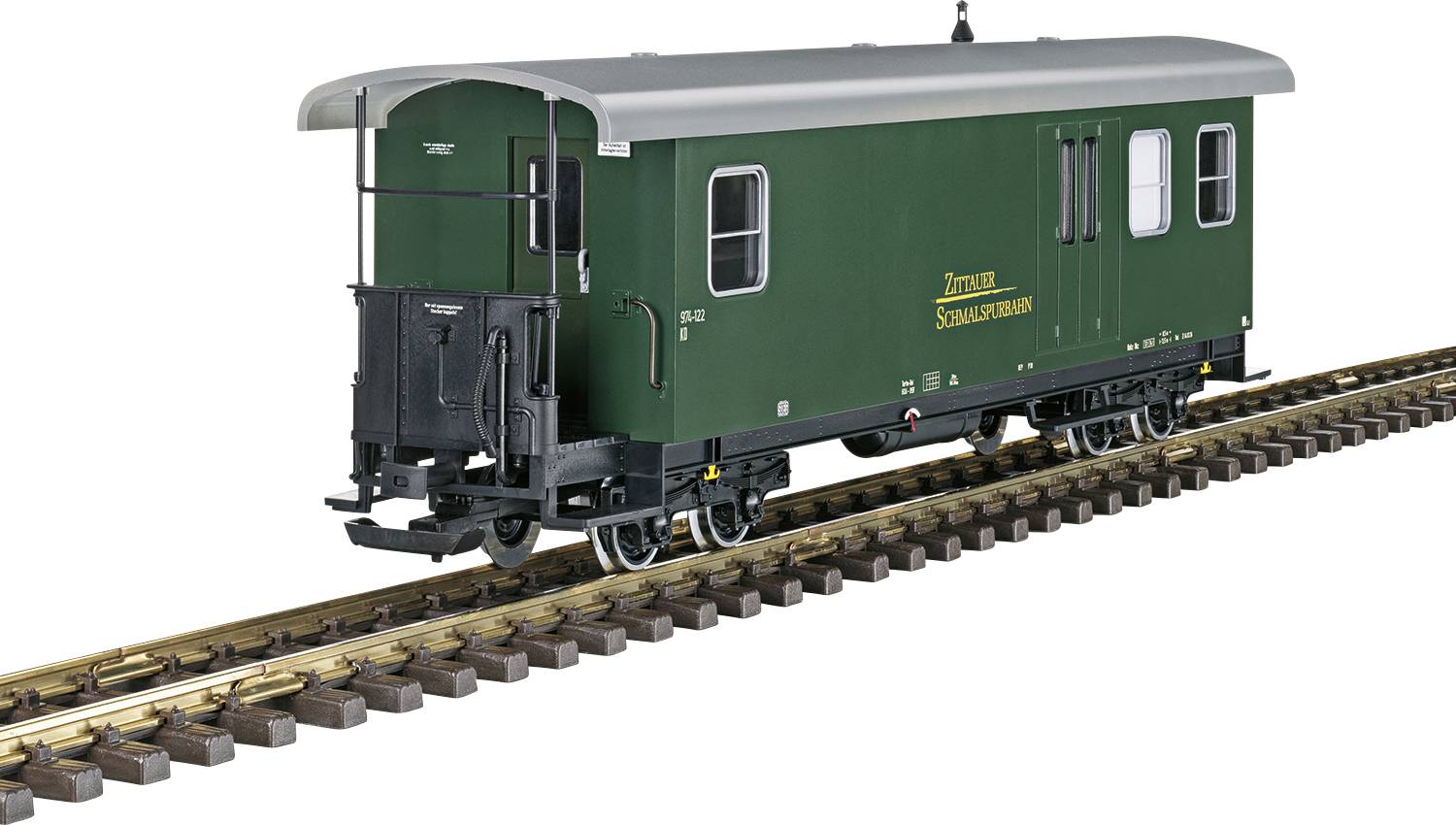 Ein grüner Zugwaggon der Zittauer Schmalspurbahn steht auf Bahngleisen. Der Waggon hat seitliche Fenster und eine Tür.