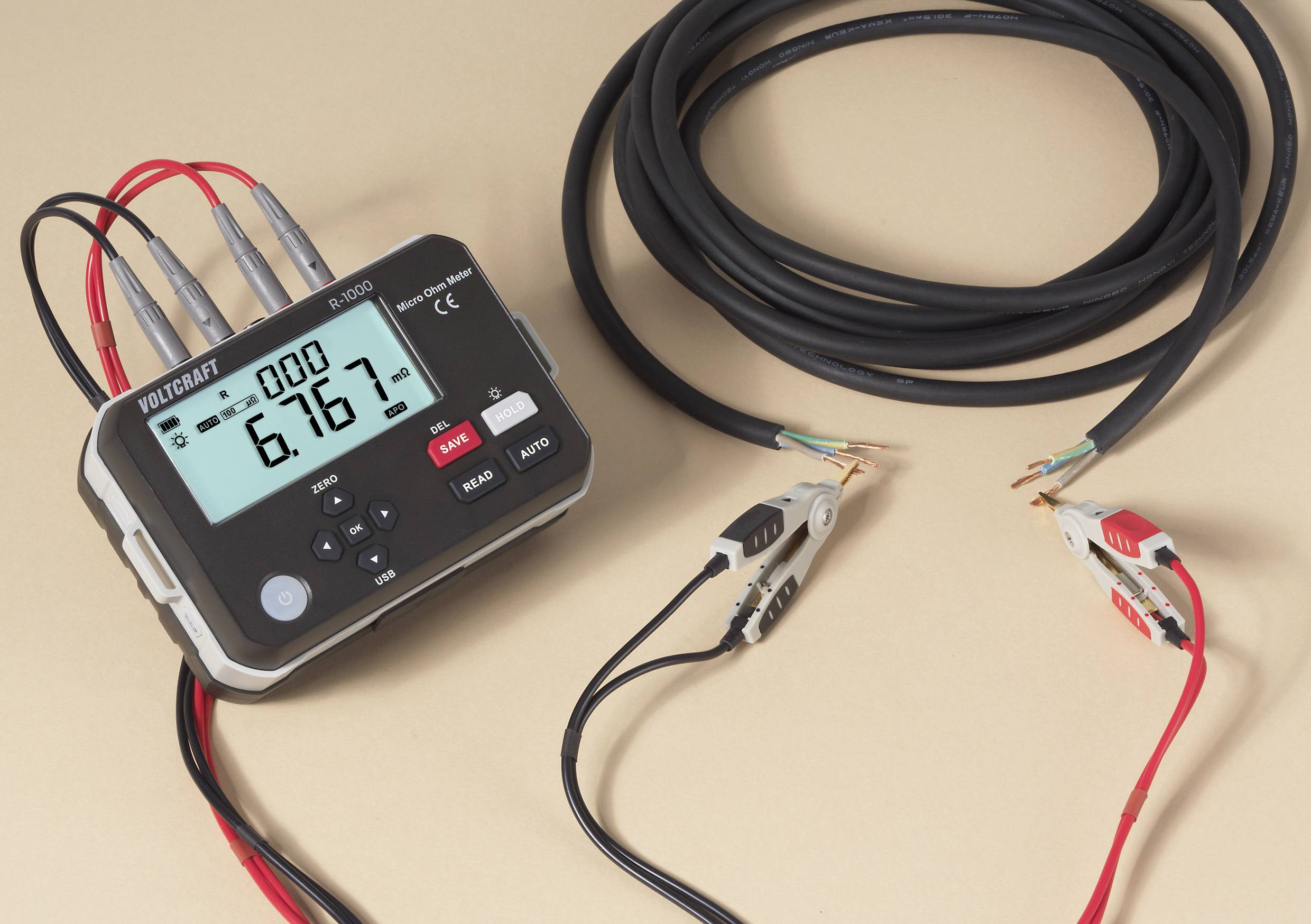 Ein digitales Multimeter, das '6,167' anzeigt, verbunden mit Kabeln und Krokodilklemmen. Das Gerät verfügt über mehrere Tasten und einen digitalen Bildschirm.