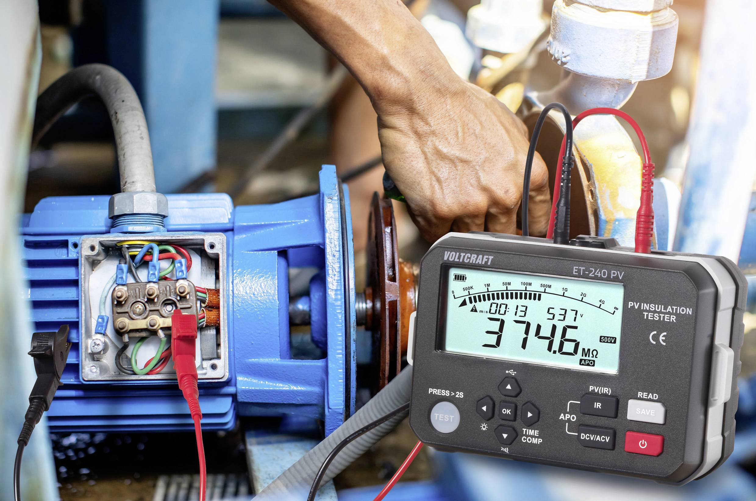 Eine Person verwendet einen digitalen Isolationstester an einem Elektromotor. Der Tester zeigt '3746 MΩ' und gibt damit die Widerstandsmessung an.