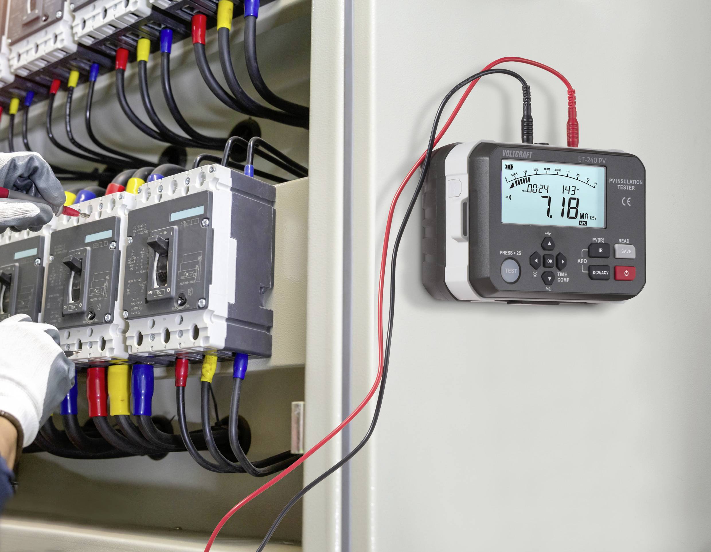 Ein Elektriker verwendet ein Multimeter, das mit einer Elektroverteilungsanlage verbunden ist, und misst Spannungs- und Stromstärkenwerte, um die Sicherheit der Ausrüstung zu gewährleisten.