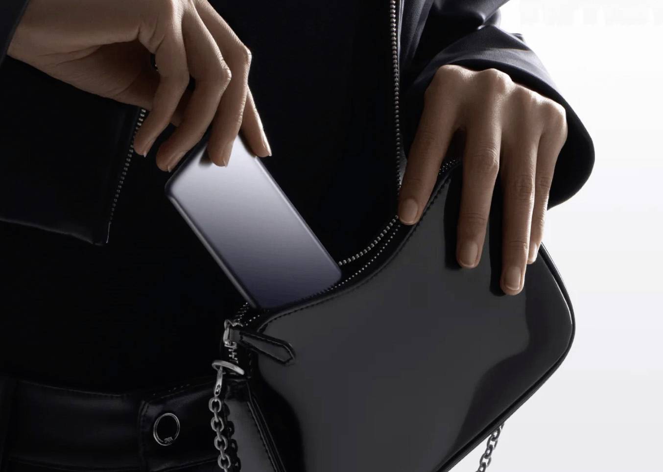 Eine Person legt ein Smartphone in eine schwarze Handtasche und unterstreicht dabei das elegante Design und die Mobilität des Geräts.