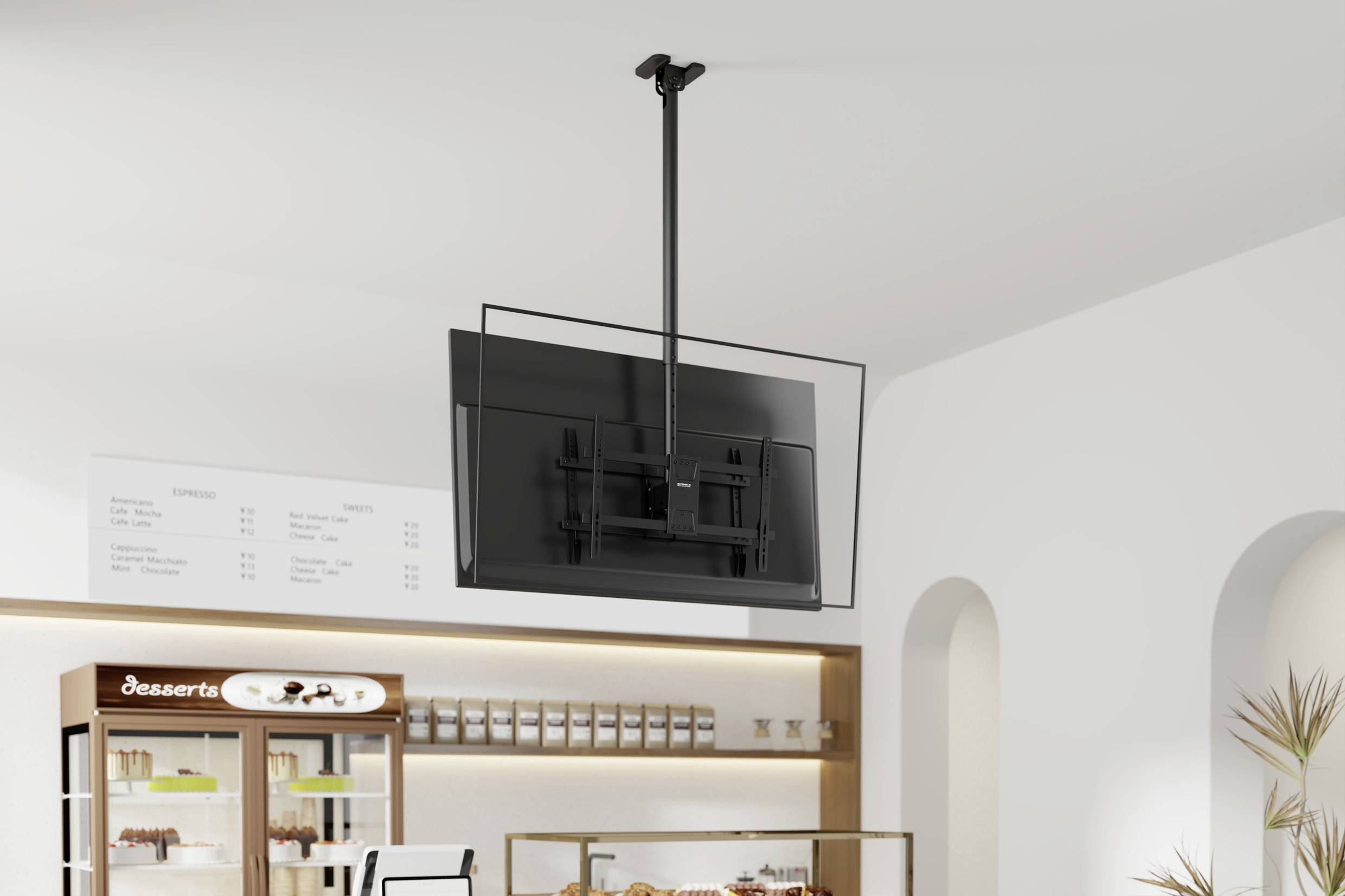 Eine an der Decke montierte, verstellbare TV-Bildschirm, der über einem modernen Café-Interieur hängt, mit einer Speisekarte und einer Backwarenvitrine im Hintergrund.