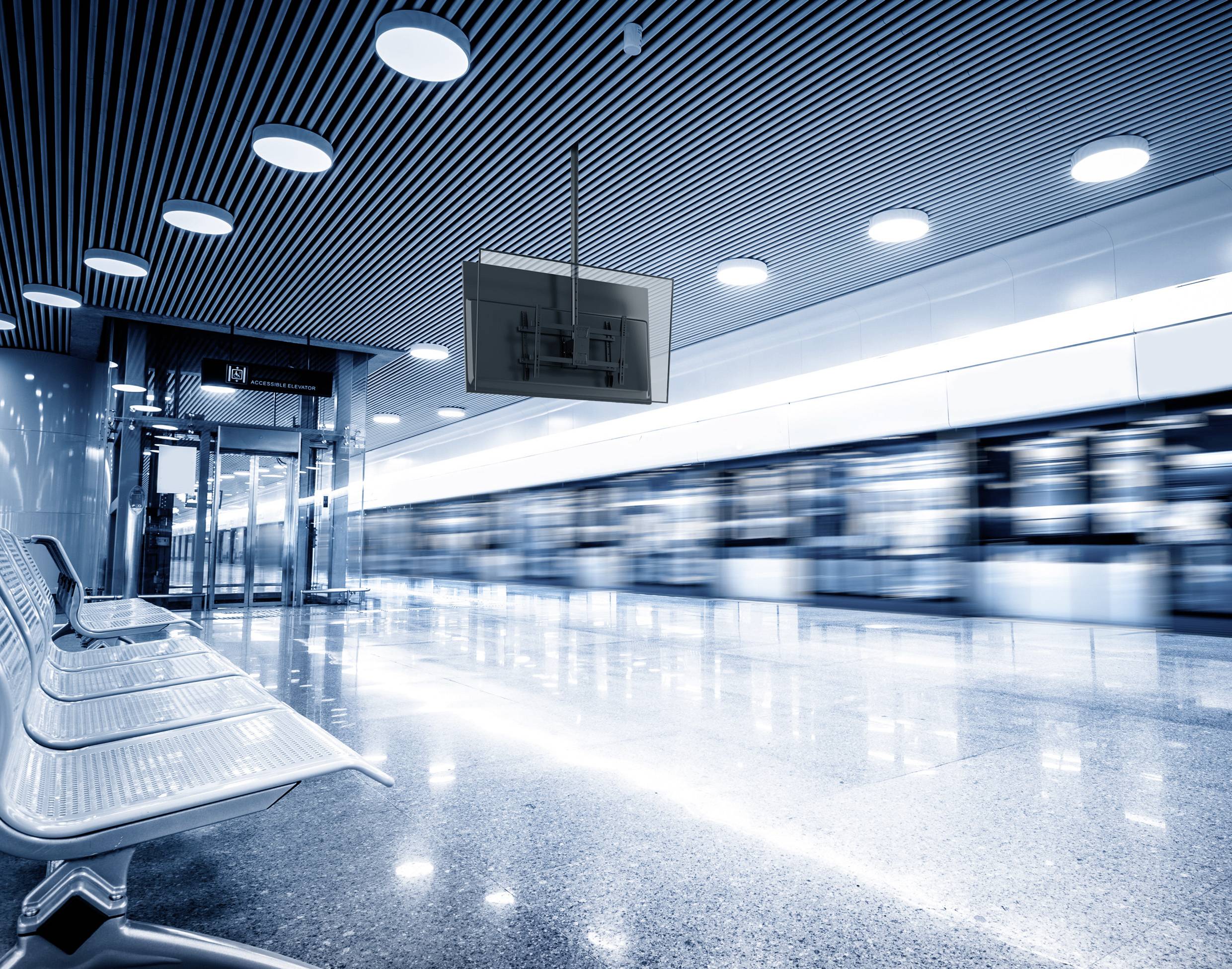Ein U-Bahnhof mit Metallbänken und einem verschwommenen Zug, der vorbeifährt und dabei hohe Geschwindigkeit und Bewegung andeutet, unter einer modernen, hell beleuchteten Decke.