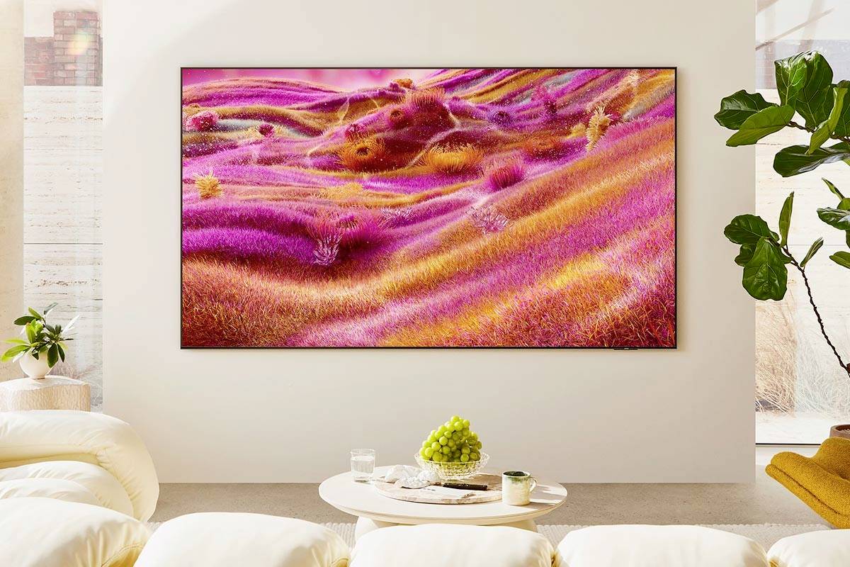 Ein großes Foto mit bunter, wellenförmiger Landschaft in Pink- und Orangetönen hängt an einer weißen Wand in einem modern eingerichteten Wohnzimmer.