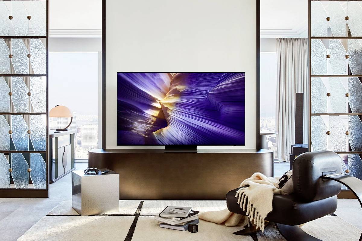 Ein modernes Wohnzimmer mit einem großen Fernseher, der ein abstraktes Bild zeigt. Im Raum befinden sich stilvolle Möbel und ein großer Fensterblick.