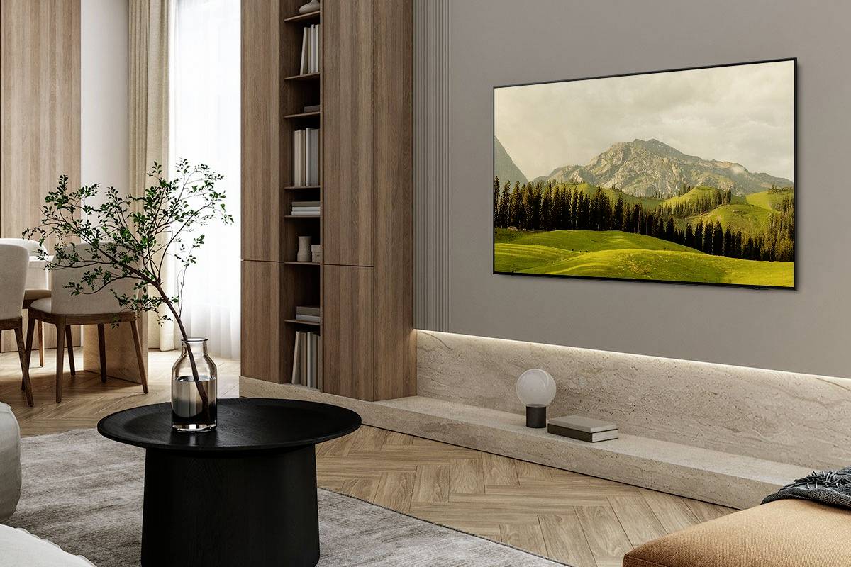 Ein Wohnzimmer mit einem Tisch, einem Regal voller Bücher und einem großen Bild mit einer Landschaft an der Wand.