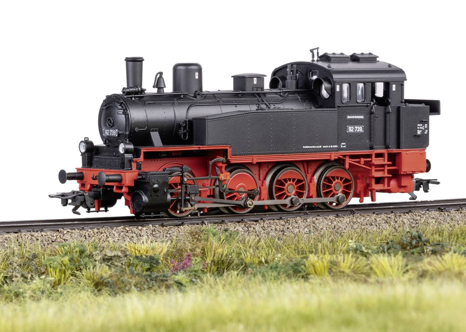 'Dampflokomotive BR 78' fährt auf einem Gleisabschnitt entlang einer Wiese. Die Lokomotive hat ein schwarzes Gehäuse mit roten Details.