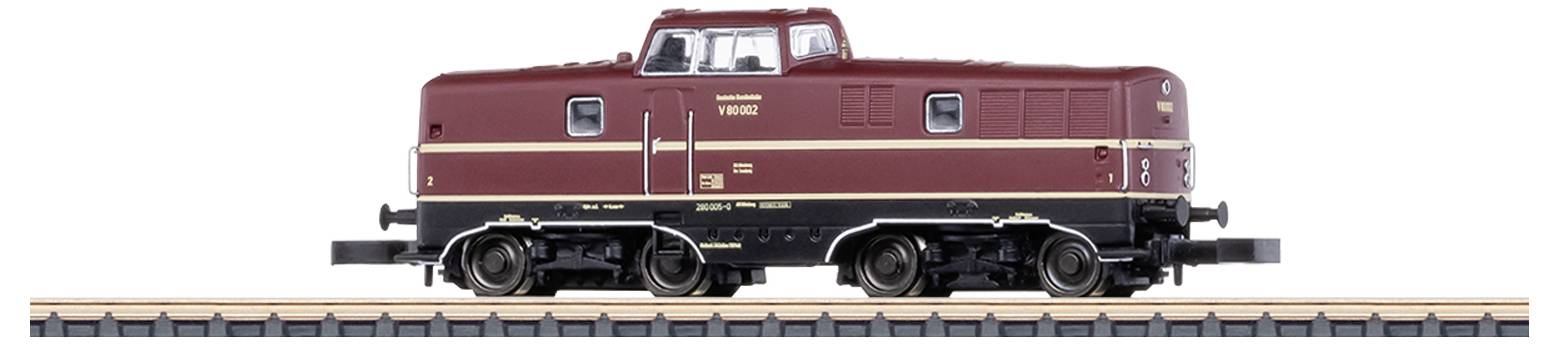 Eine dunkelrote Modelllokomotive im Maßstab H0 steht auf einem Gleisabschnitt. Sie hat gelbe und schwarze Details und wirkt detailliert gestaltet.