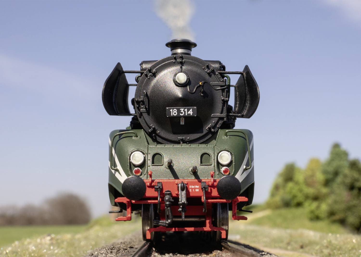 Alte Dampflokomotive 18 314 auf Schienen in ländlicher Umgebung, blauer Himmel im Hintergrund.