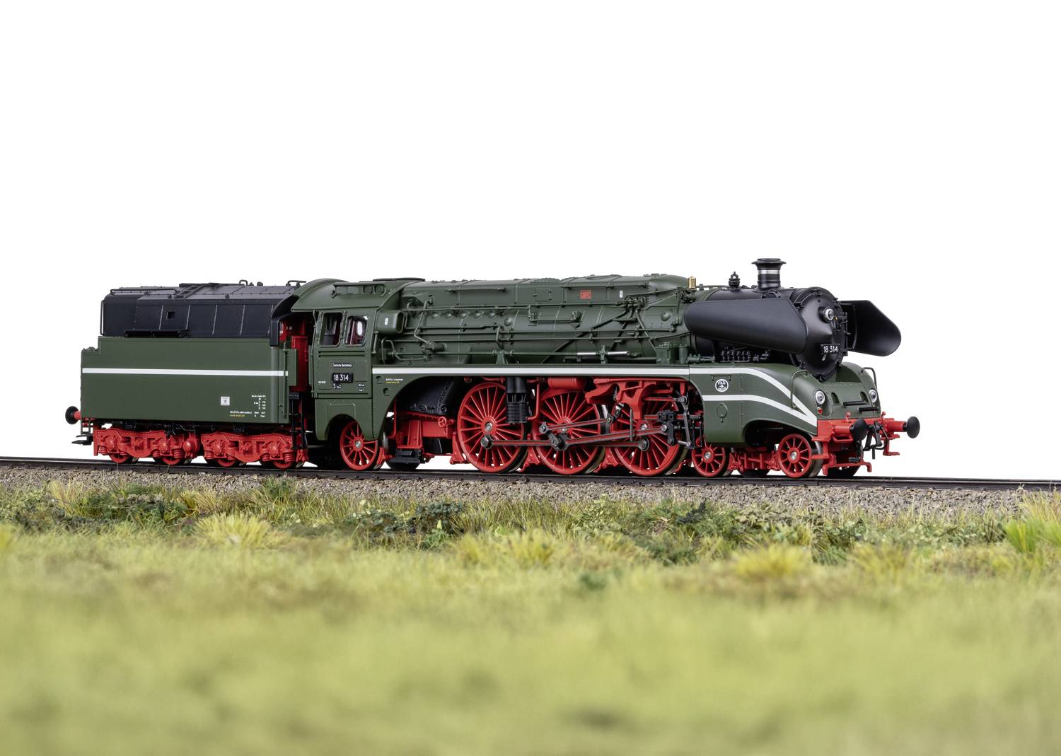Eine grüne Dampflokomotive mit roten Rädern auf Gleisen, umgeben von Gras. Sie ist detailreich modelliert und scheint im Maßstab verkleinert zu sein.