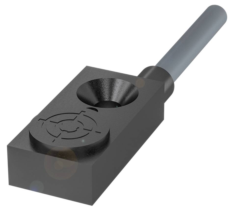 Ein schwarzes Metallbauteil mit einem zylindrischen Griff und einer kreisförmigen Einfräsung auf der Oberfläche.