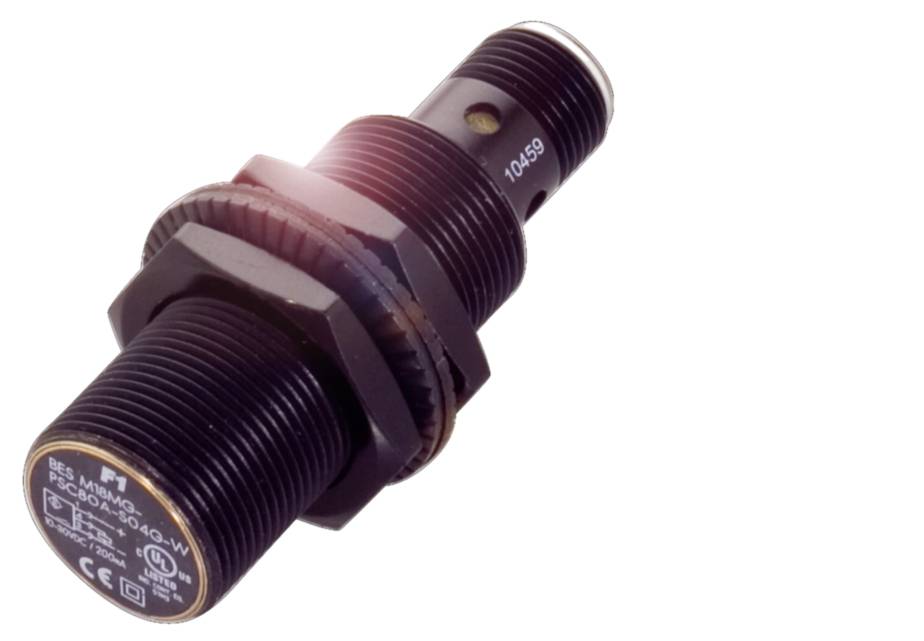 Ein schwarzer, zylindrischer Sensor mit Gewinde, Herstellerinformationen und Produktnummer sichtbar, reflektiert Licht.