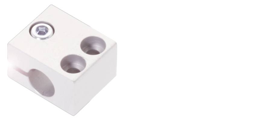 Ein silberner Metallblock mit vier Löchern, eines davon mit einer Schraube. Der Block ist minimalistisch und technisch gestaltet.