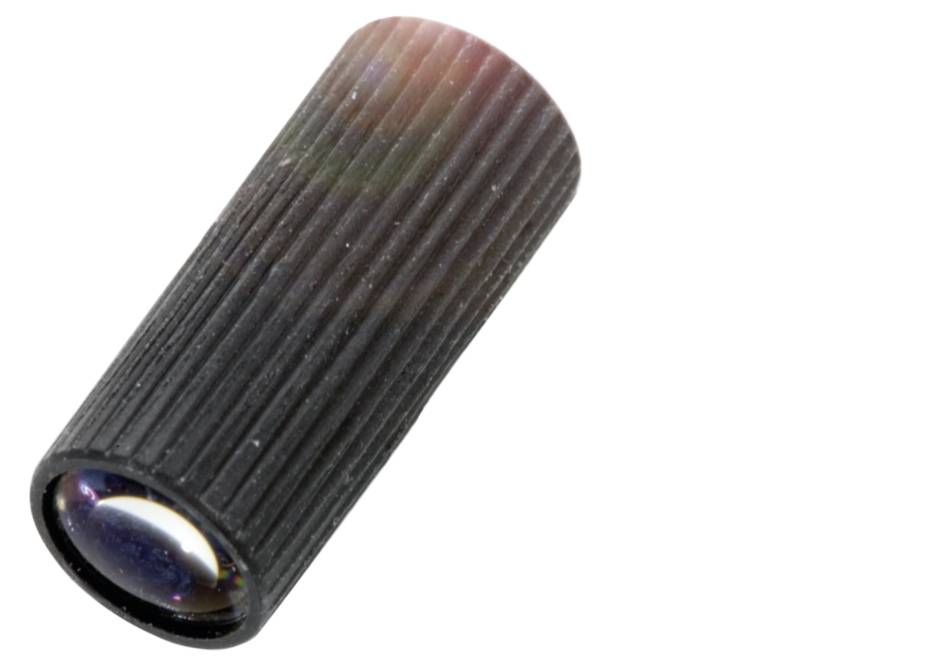 Ein zylindrisches, strukturiertes Schiebeventil aus schwarzem Material, das schräg nach oben liegt. Es hat ein sichtbares Glasobjektiv.