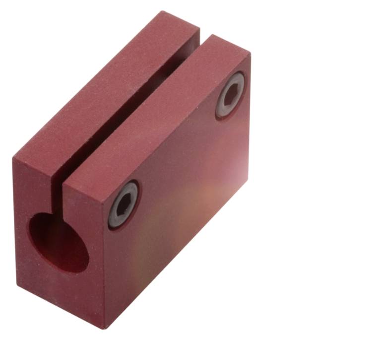 Ein roter Metallblock mit einer vertikalen Einkerbung und zwei Schraubenöffnungen an der Oberseite, möglicherweise ein Maschinenteil.