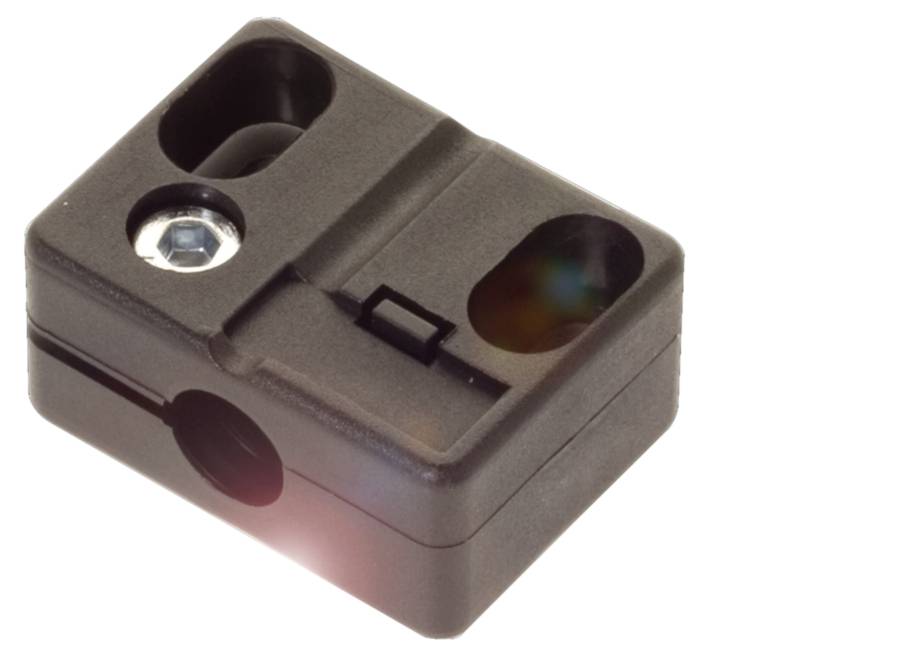 Ein schwarzer, rechteckiger Gegenstand mit drei Öffnungen und einer silbernen Schraube. Möglicherweise Teil eines technischen Geräts.