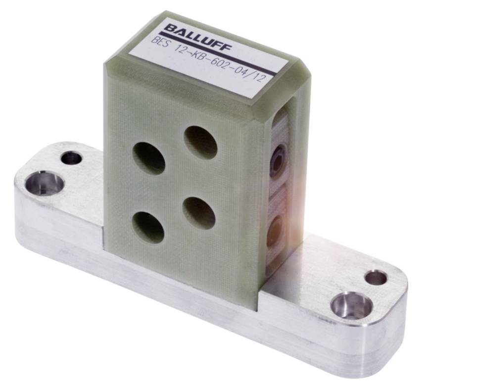 Ein rechteckiger, olivgrüner Sensor mit vier kreisförmigen Öffnungen auf einem silbernen Metallträger. Oben ist der Text 'BALLUFF' sichtbar.